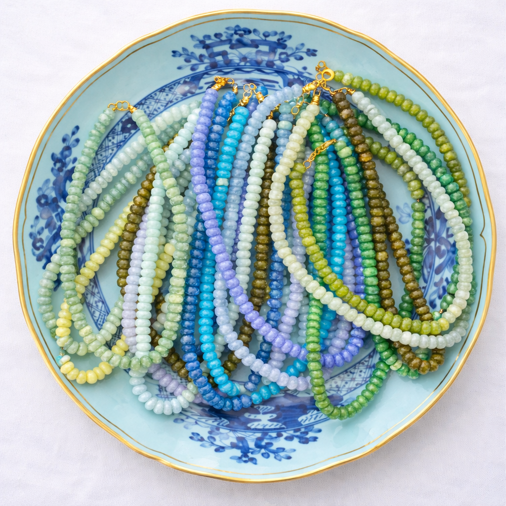Colorful beaded necklaces on a decorative plate with blue floral patterns