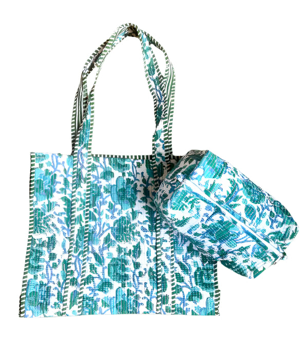 A quilted tote bag with blue and green floral block print design, featuring a sturdy handle and a zipper.