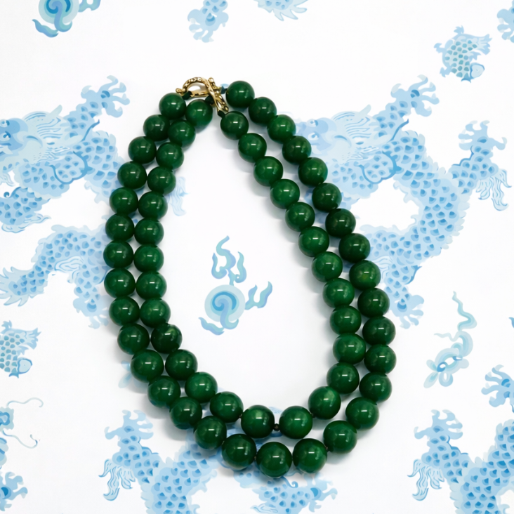 Green beaded necklace on a decorative blue and white background
