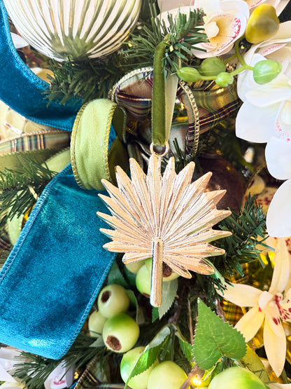 Decorative palm leaf ornament on a Christmas tree with greenery and ornaments.